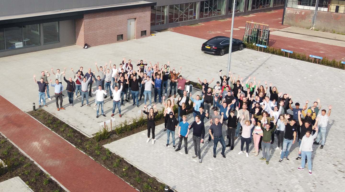 Het voltallige Azerty-team juicht met de armen omhoog voor het bedrijfspand