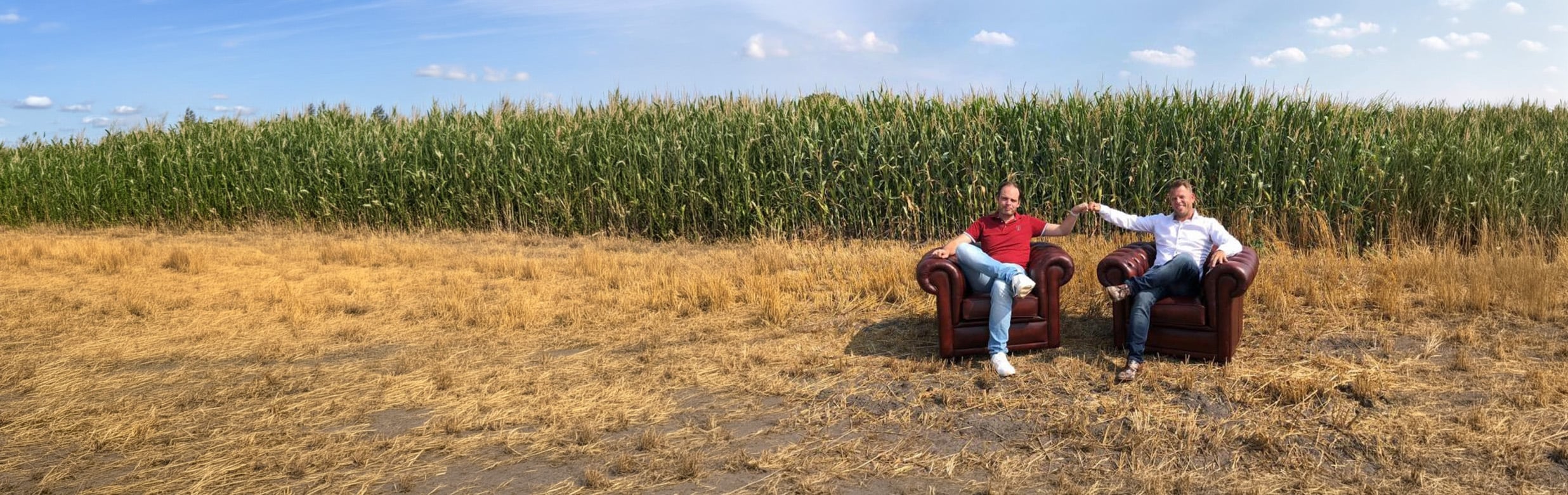 Oprichters Jeroen en Richard van Azerty zitten in twee Chesterfield fauteuils voor een ma&iuml;sveld