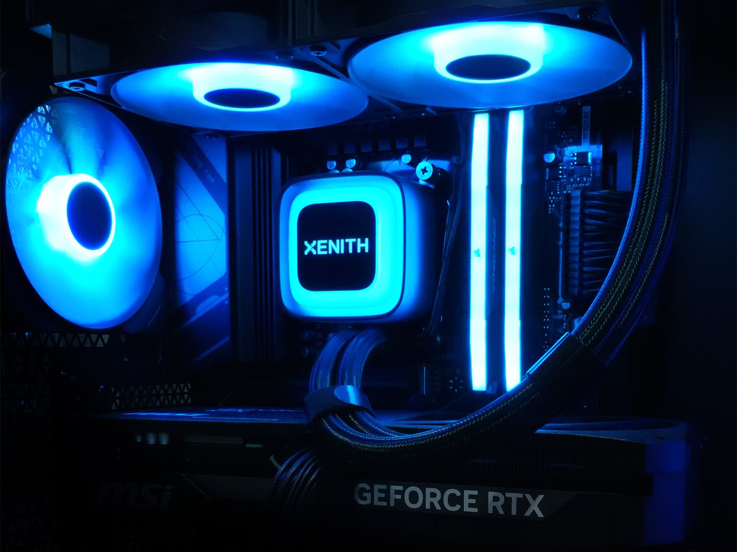 Binnenkant van een Xenith gaming-pc met blauw verlichte fans, Xenith-waterkoeling en GeForce RTX videokaart
